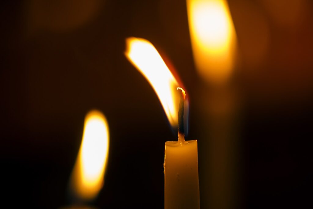 An image of a candle burning in the foreground, a flame of an unseen candle, and a candle burning in the background. A light in the darkness. Revealing sin.
Image by Engin Akyurt from Pixabay 