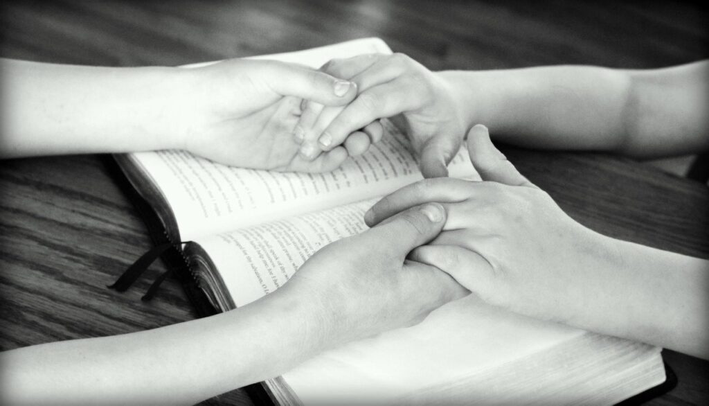 Two children holding hands on a Bible in prayer.
Image by Godsgirl_madi from Pixabay 