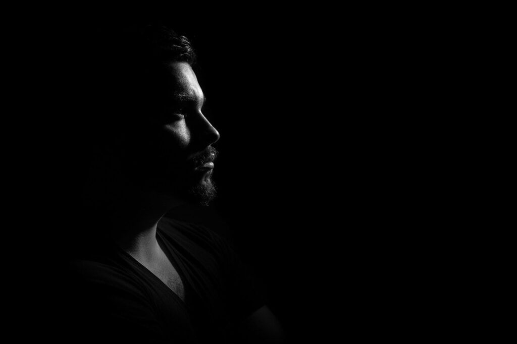 The side profile of a man, staring without emotion. Darkness all around him.
Image by Mihai Paraschiv from Pixabay 