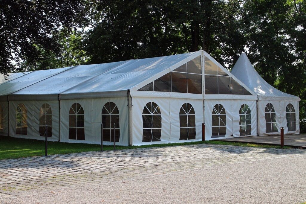 A large white tent with arched windows, set in among a grove of trees.  Perfect for an old-time church revival.
Image by Manfred Antranias Zimmer from Pixabay