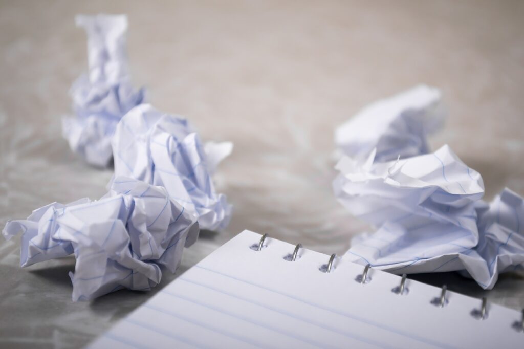 Several wads of paper next to a blank notebook. 