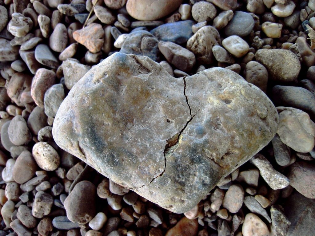 Rock shaped like a heart, cracked, broken, laying on a bed of smaller rocks. love, hate
Image by Miriam Müller from Pixabay 