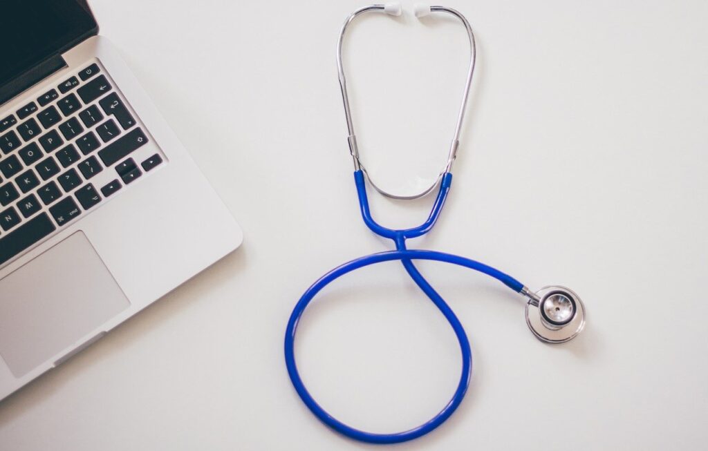 Photo of a laptop and stethoscope on a white table. 
medical, doctor, 
Image by StockSnap from Pixabay 