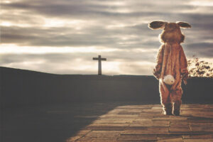 a photo of the back of a giant easter bunny looking on to cross in the distance.