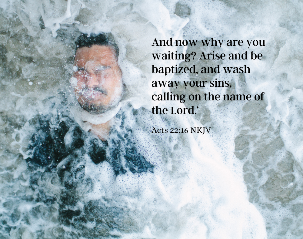 A man laying in ocean water which is foamy all around him. The words to Acts 22:16